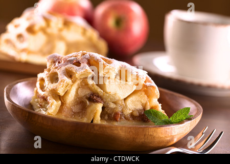 Apfelstrudel mit Rosinen mit Kaffeetasse auf der Rückseite Stockfoto