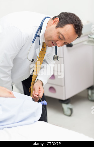 Arzt überprüft die Reflexe der das Knie eines Patienten Stockfoto