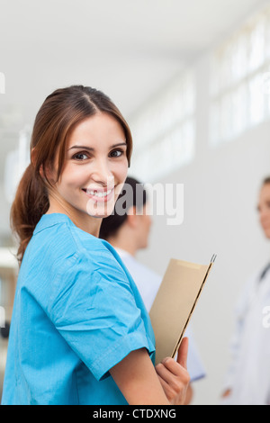 Krankenschwester während des Betriebs Dateien lächelnd und mit einem Arzt und einem Patienten stehen Stockfoto