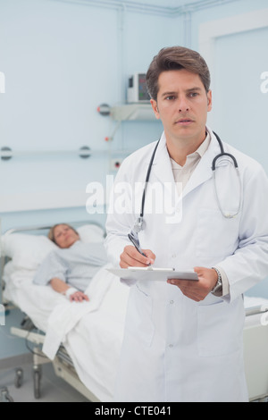 Nachdenklich Arzt schriftlich auf einem Klemmbrett Stockfoto