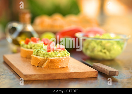 Snack Baguette Scheiben mit Avocado Creme, Tomaten und Zwiebeln auf Holzbrett Stockfoto