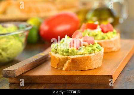 Snack Baguette Scheiben mit Avocado Creme, Tomaten und Zwiebeln auf Holzbrett Stockfoto