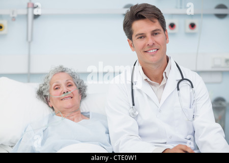 Arzt sitzt auf dem Bett neben einem Patienten Stockfoto