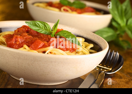 Spaghetti mit Tomatensoße, garniert mit einem Blatt frischem Basilikum (selektiven Fokus, Fokus auf das Basilikum in der Front) Stockfoto