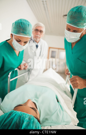 Patient liegt auf einem medizinischen Bett neben Ärzten Stockfoto