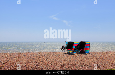 Zwei Menschen sitzen in Liegestühlen am Strand Stockfoto