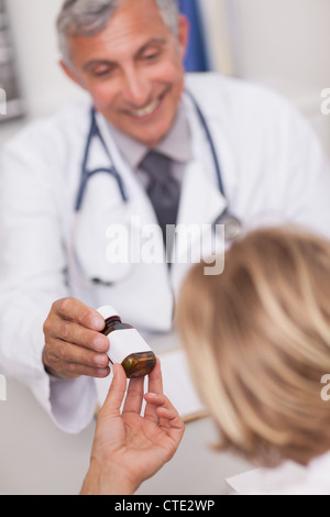 Arzt geben eine Flasche von Drogen zu einem Patienten Stockfoto