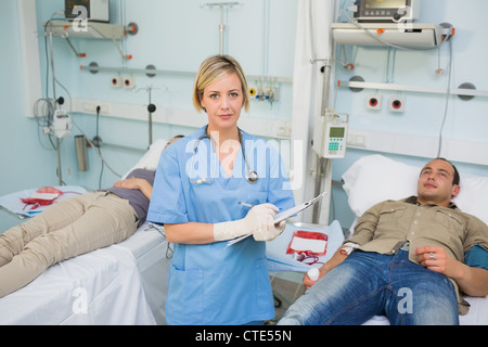 Krankenschwester mit einem Klemmbrett neben transfundierten Patienten Stockfoto