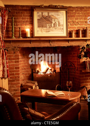 gemütliche Kamin in einem britischen Pub mit einem Glas Wein und einem Buch Stockfoto