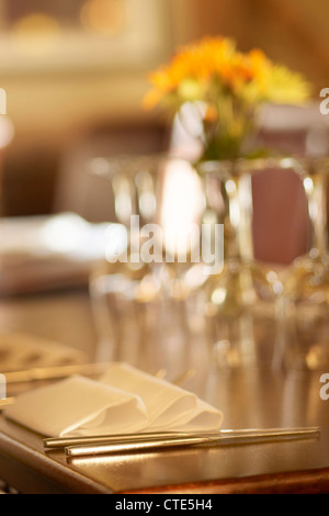Restaurant-Tischdekoration mit Ledersesseln, Gläser und Blumen Stockfoto