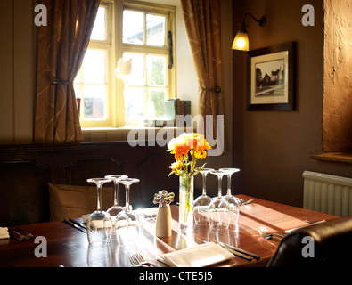 Restaurant-Tischdekoration mit Ledersesseln, Gläser und Blumen Stockfoto