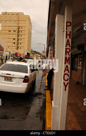 Ein Mann kehrt Wasser aus einer Straße, die einst mit amerikanischen Touristen in Nogales, Sonora, Mexiko beschäftigt war. Stockfoto