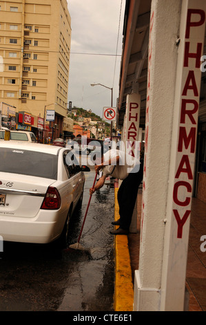 Ein Mann kehrt Wasser aus einer Straße, die einst mit amerikanischen Touristen in Nogales, Sonora, Mexiko beschäftigt war. Stockfoto