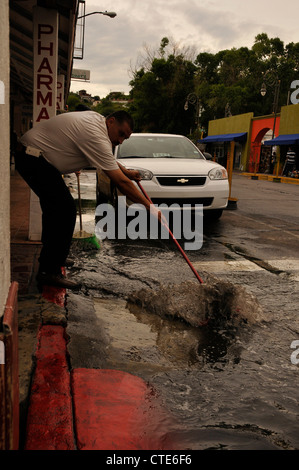 Ein Mann kehrt Wasser aus einer Straße, die einst mit amerikanischen Touristen in Nogales, Sonora, Mexiko beschäftigt war. Stockfoto