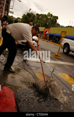 Ein Mann kehrt Wasser aus einer Straße, die einst mit amerikanischen Touristen in Nogales, Sonora, Mexiko beschäftigt war. Stockfoto