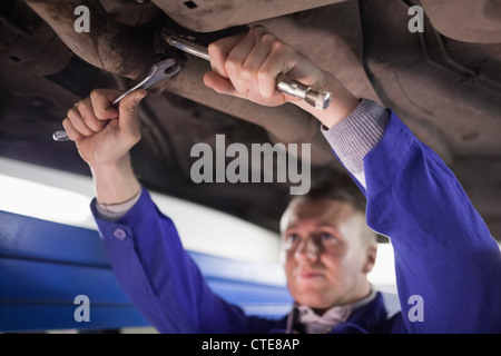 Konzentrierte Mechaniker ein Auto zu reparieren, während Sie mit Werkzeugen Stockfoto
