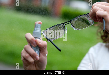 Reinigung von Brillen mit einem Spray auf cleaner Stockfoto