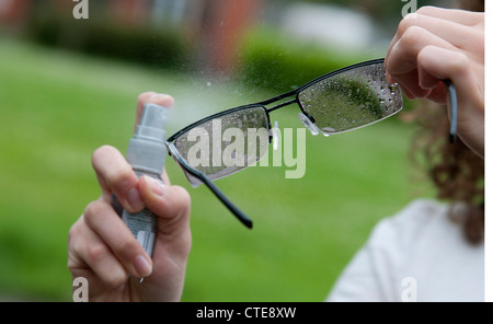 Reinigung von Brillen mit einem Spray auf cleaner Stockfoto