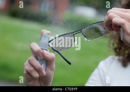 Reinigung von Brillen mit einem Spray auf cleaner Stockfoto