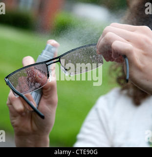 Reinigung von Brillen mit einem Spray auf cleaner Stockfoto