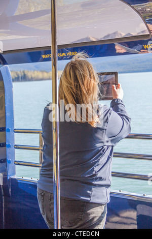 Tourist mit iPad, Foto von Kenai Lake aus Alaska Railroad Bahnfahrt zwischen Seward und Anchorage, Alaska zu nehmen. Stockfoto