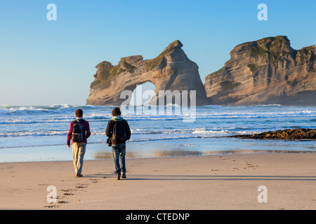 Zwei Besucher zu Fuß auf Wharariki Beach in der Region Tasman in Neuseeland in den Abend. Stockfoto