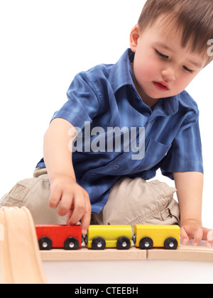 Zwei Jahre alten Jungen Plaing mit einem Holzspielzeug Zug auf einer Eisenbahn Stockfoto