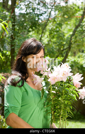 Frau im Garten tragen eingemachte Lilien Stockfoto