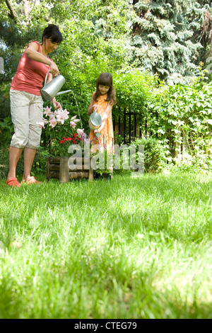 Mutter und Tochter, die Bewässerung von Pflanzen im Garten Stockfoto