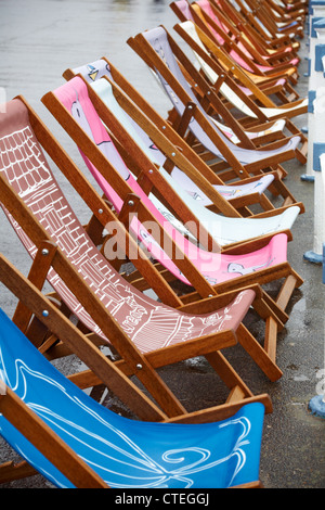 Die Weymouth Esplanade ist mit 500 Liegestühlen und Liegestühlen ausgestattet, die von den Einheimischen am Weymouth Beach, Dorset UK, an einem regnerischen Tag im Juli entworfen wurden Stockfoto