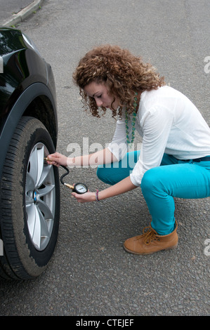 Junge Teenager Autofahrer mit einem Reifen Manometer Stockfoto