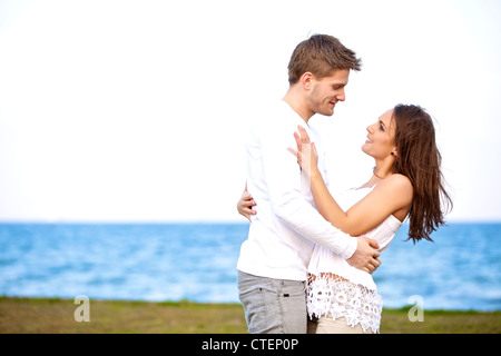 Porträt eines jungen romantischen Paares an einem Strand einander liebevoll betrachtend Stockfoto