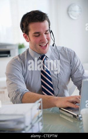 USA, New Jersey, Jersey City, Mann mit Kopfhörer am Laptop arbeiten Stockfoto