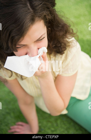Frau bläst, Jersey City, New Jersey, USA Nase sitzend auf Rasen Stockfoto