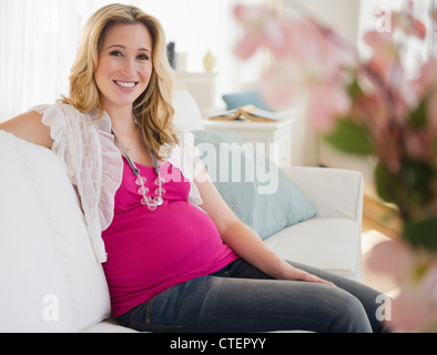 USA, New Jersey, Jersey City, schwangere Frau auf dem Sofa sitzen Stockfoto