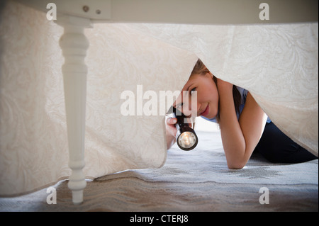 USA, New Jersey, Jersey City, Frau mit Taschenlampe suchen unter Bett Stockfoto