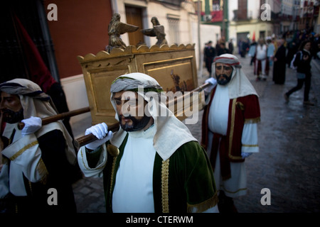Maskierte Männer gekleidet als biblischen Figuren tragen eine Darstellung des Bogens des Bundes über Ostern in Spanien Stockfoto