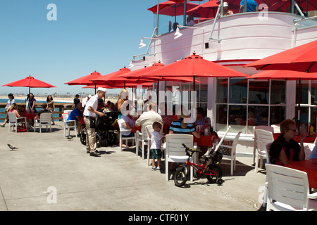 Freunde und Familie genießen Sie eine Mahlzeit im Schatten der Sonnenschirme in Rubys Restaurant am Balboa Pier Newport Beach Kalifornien Stockfoto