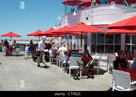 Freunde und Familie genießen Sie eine Mahlzeit im Schatten der Sonnenschirme in Rubys Restaurant am Balboa Pier Newport Beach Kalifornien Stockfoto