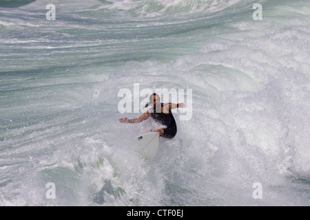 Ein Mann am Huntington Beach Pier California umgeben mit Wildwasser Rafting als die Welle bricht um ihn herum surfen Stockfoto