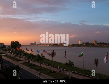 Flussfront von Phnom Penh durch Mekong Fluß in der Abenddämmerung mit Sonnenuntergang und Menschen zu Fuß entlang dem Rand des Wassers Stockfoto