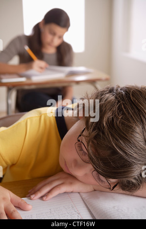 USA, California, Los Angeles, junge (10-11) Nickerchen auf Schreibtisch mit Mädchen (12-13) im Hintergrund Stockfoto
