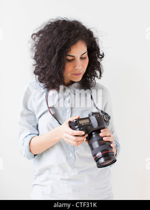 Schöne junge Frau, die professionelle Kamera halten Stockfoto