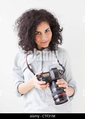 Porträt der schönen jungen Frau hält Profikamera Stockfoto