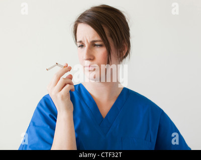 Junge Frau brach Zigarette zu prüfen Stockfoto