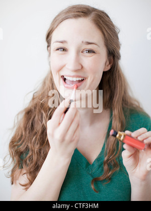 Glückliche junge Frau Auftragen von Lippenstift Stockfoto
