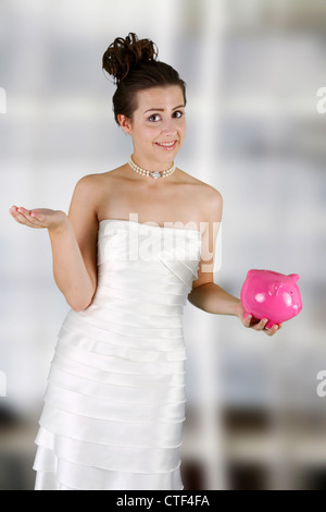 Frau in einem Brautkleid mit Sparschwein Stockfoto