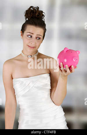 Frau in einem Brautkleid mit Sparschwein Stockfoto