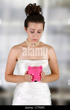 Frau in einem Brautkleid mit Sparschwein Stockfoto
