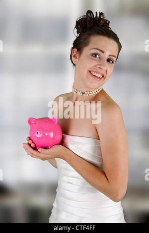 Frau in einem Brautkleid mit Sparschwein Stockfoto